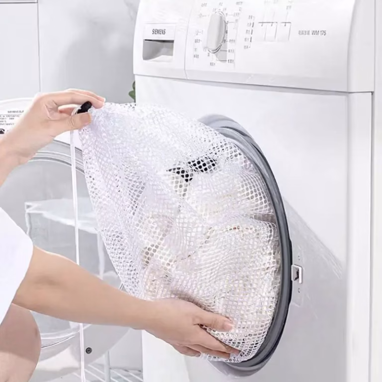 Person placing a mesh bag of delicates into a front-load washing machine