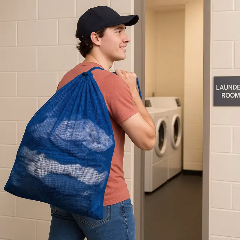 Student with a blue heavy duty mesh bag heading to a dorm laundry room.